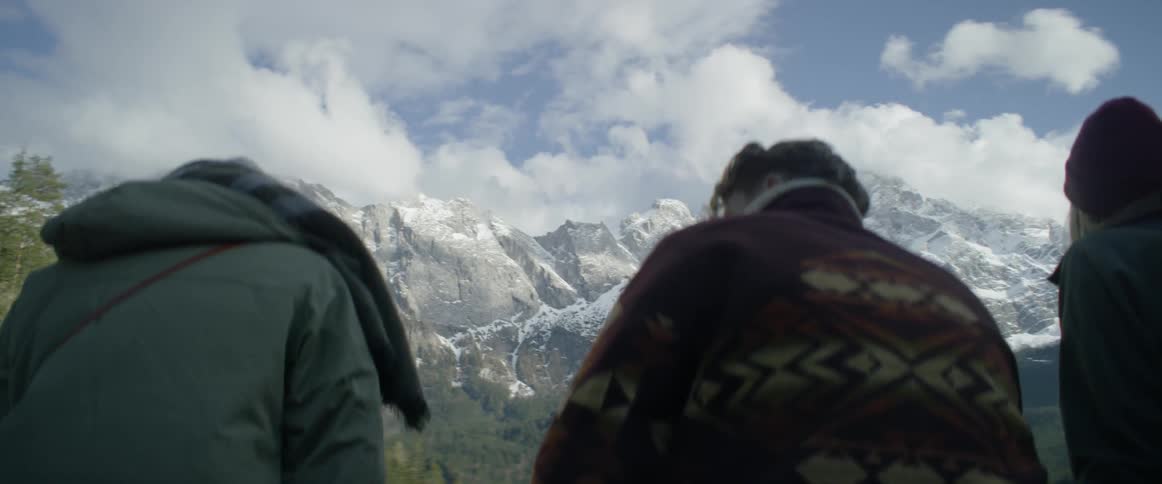 A group of friends are standing next to each other looking at a mountain range