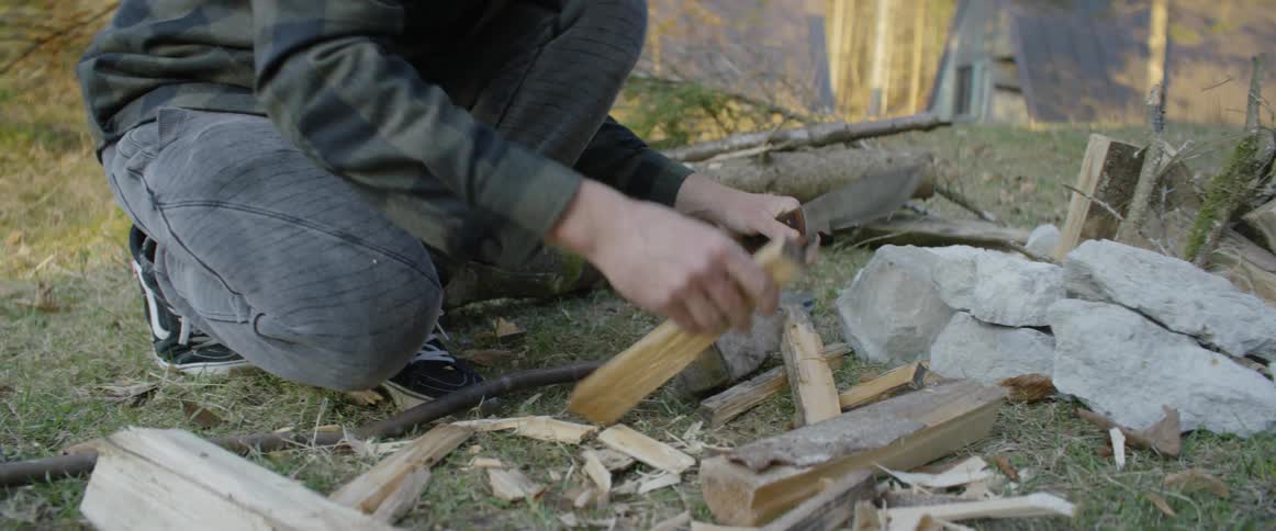 A man is hitting a knife into a piece of wood