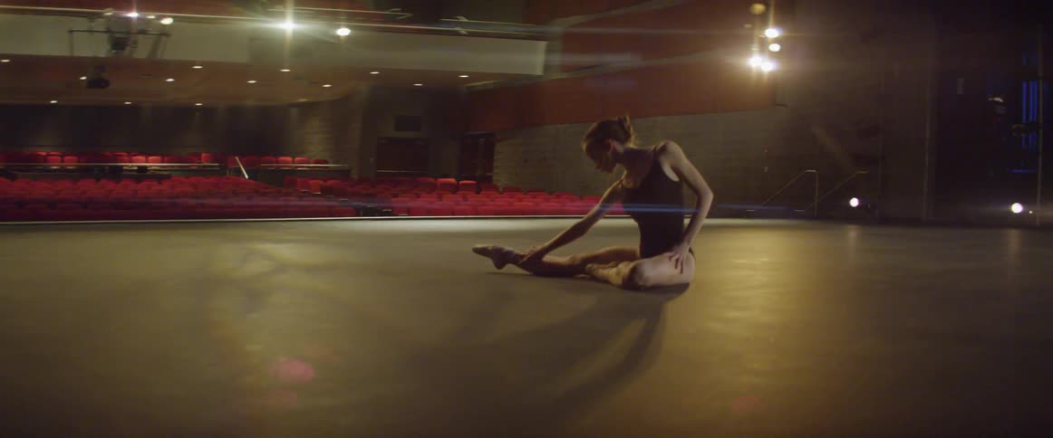 A ballerina stretches on stage