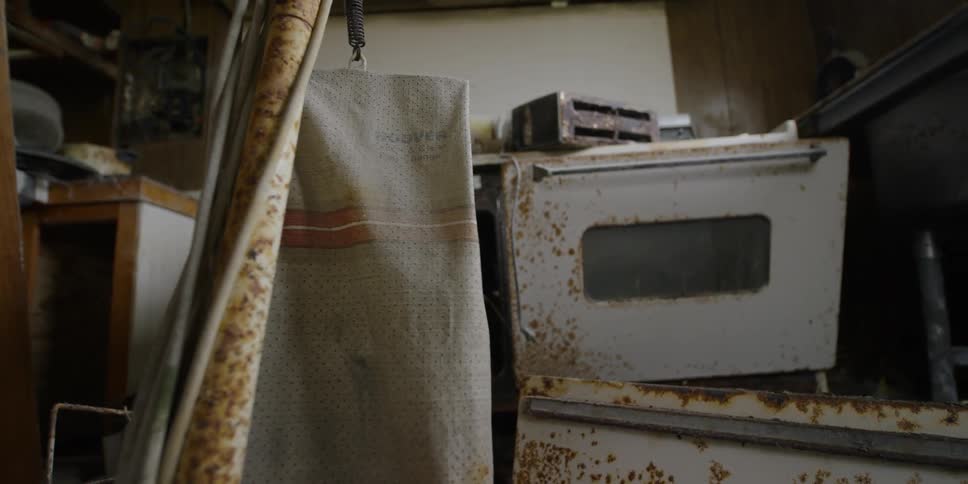 A vacuum cleaner stands in a destroyed and abandoned kitchen