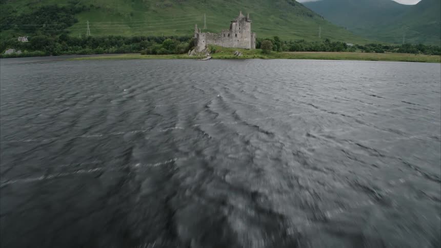 Lake water ripples next to an old stone building
