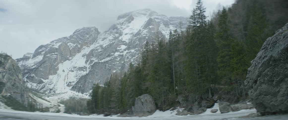 A frozen lake, a forest and a mountain in the background