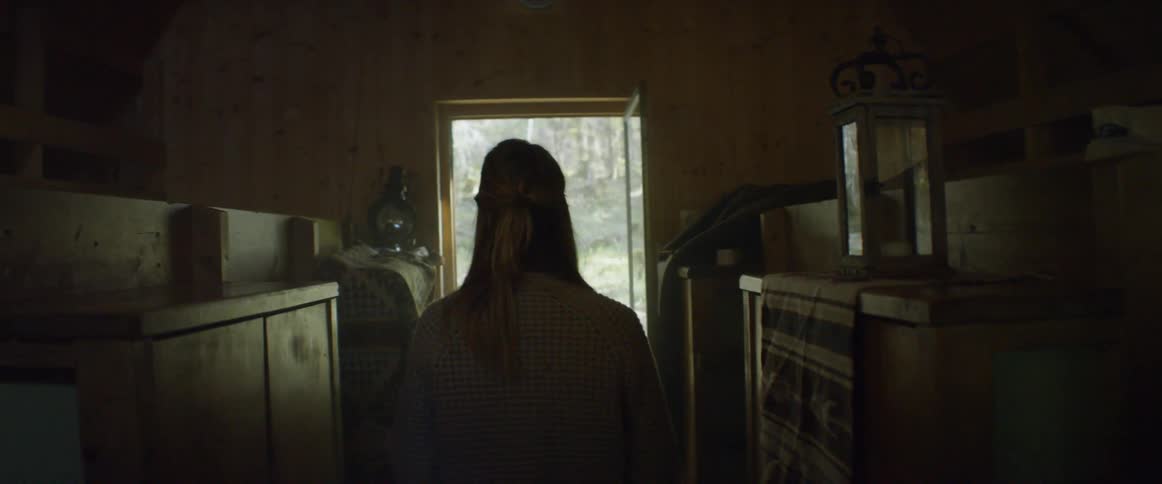 A woman walks through a cabin to an open door