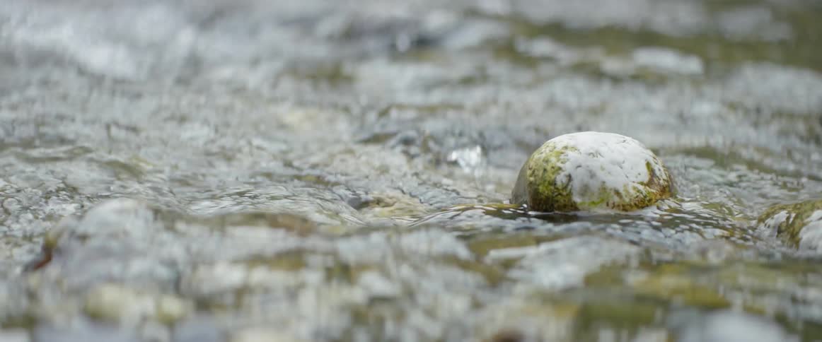 Water in creek flowing past a rock