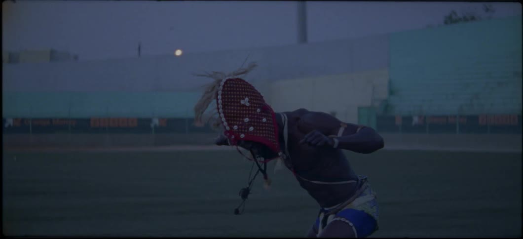 A man wearing a headdress is dancing in the middle of a stadium