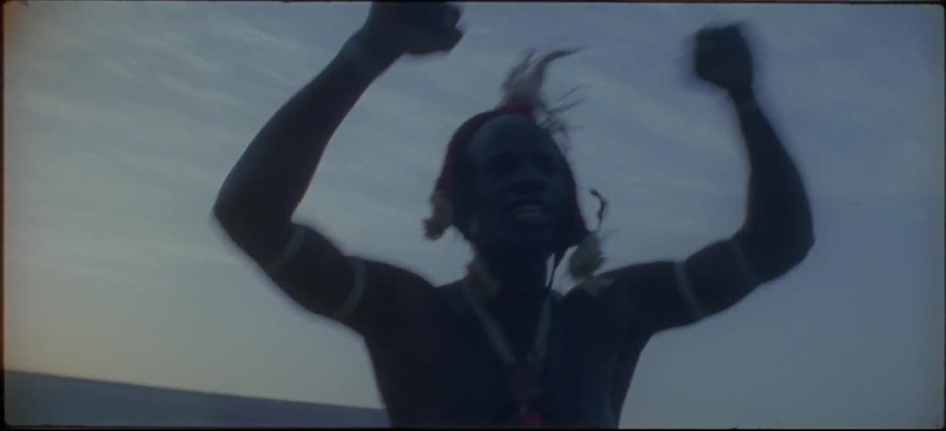 A man in a headdress is dancing and cheering in an empty stadium