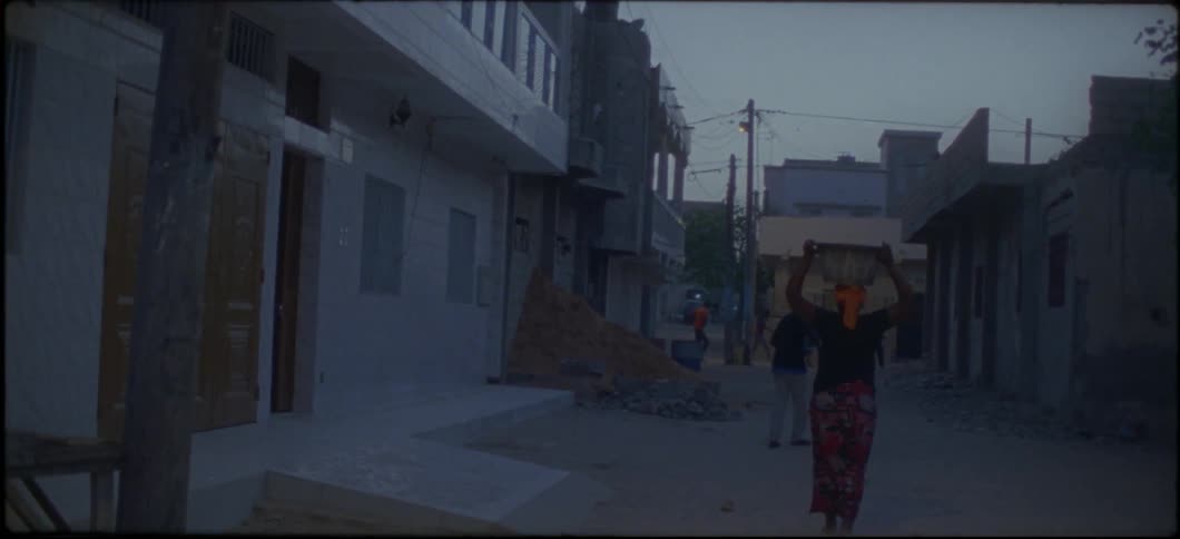 A woman is walking down the street with a basket on her head