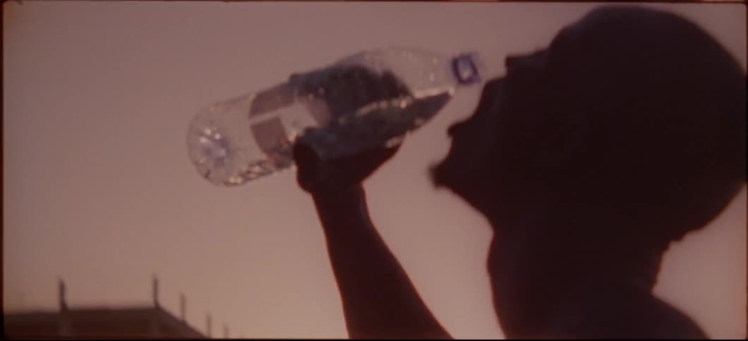 A man drinks some water on the beach