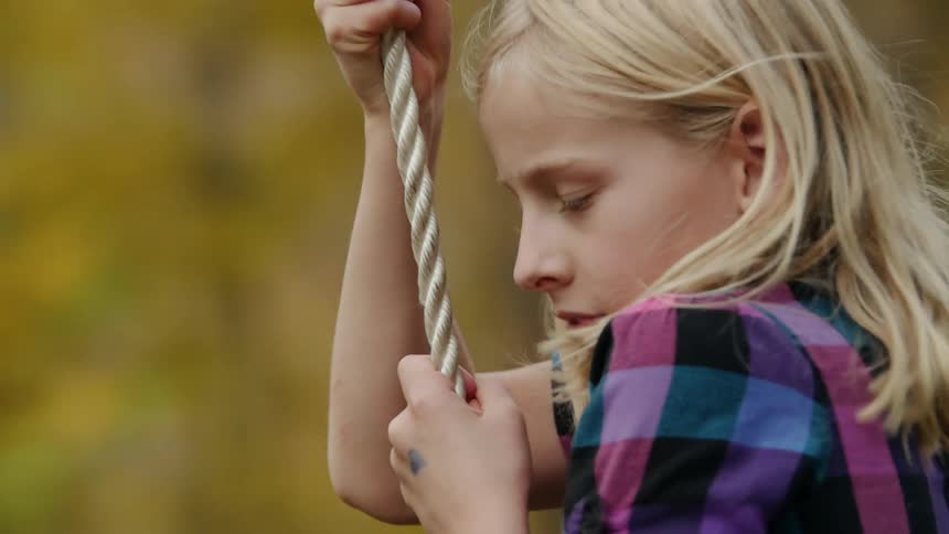 A child swings from a rope swing outside