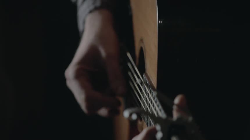 A person's hands playing an acoustic guitar