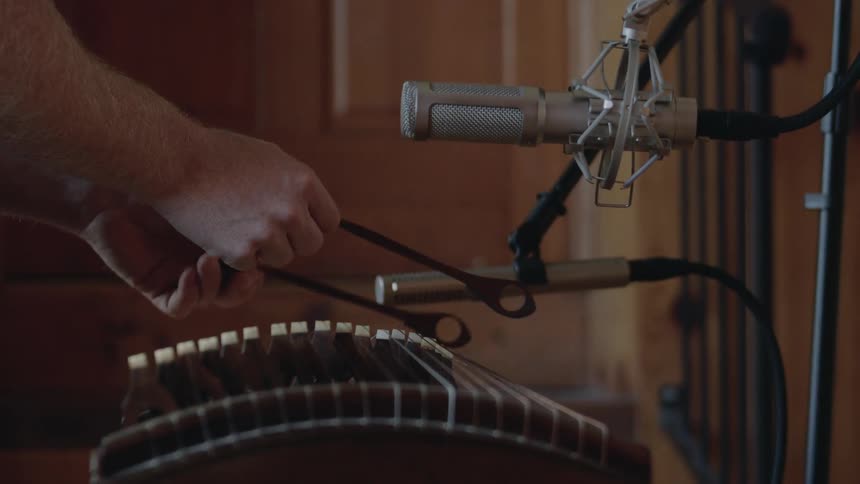 A man hits an instrument with strikers under a microphone
