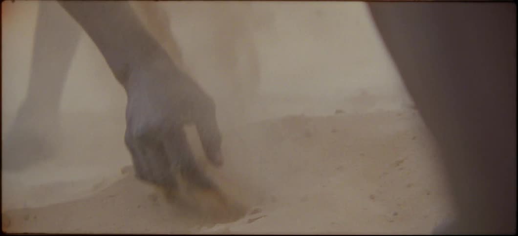 Two people are shoveling sand with their hands