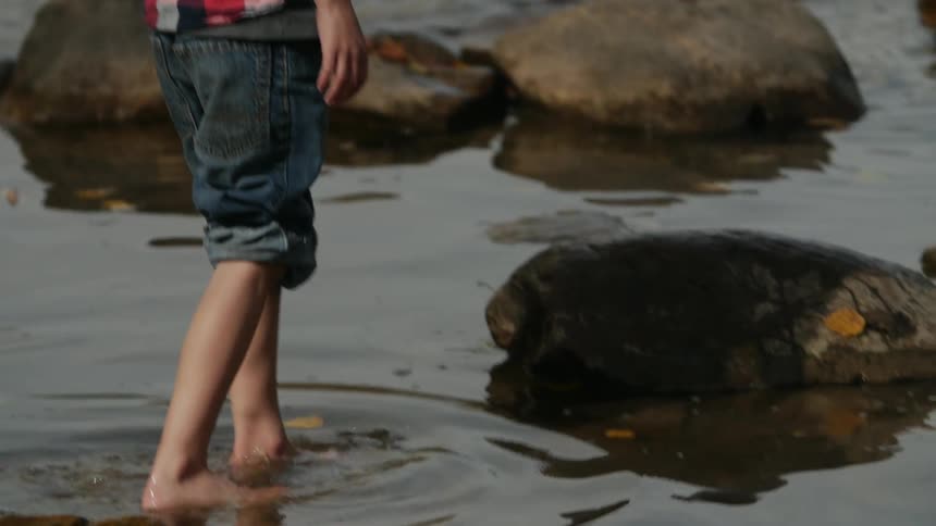 A boy throws a rock into a river