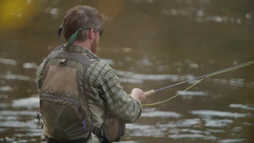 A man is fly fishing in the creek