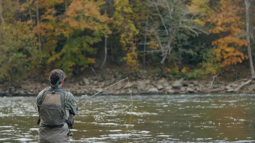 A fisherman casts his line into the river