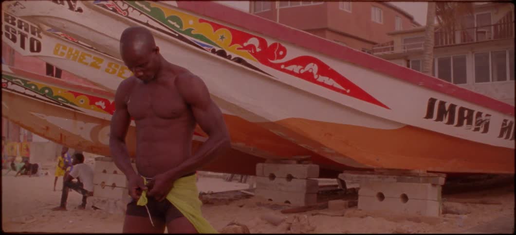 A man on a beach ties a scarf around his shorts