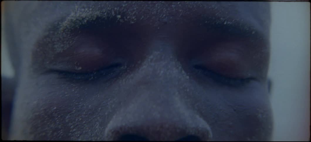 A man with sand on his face opens his eyes