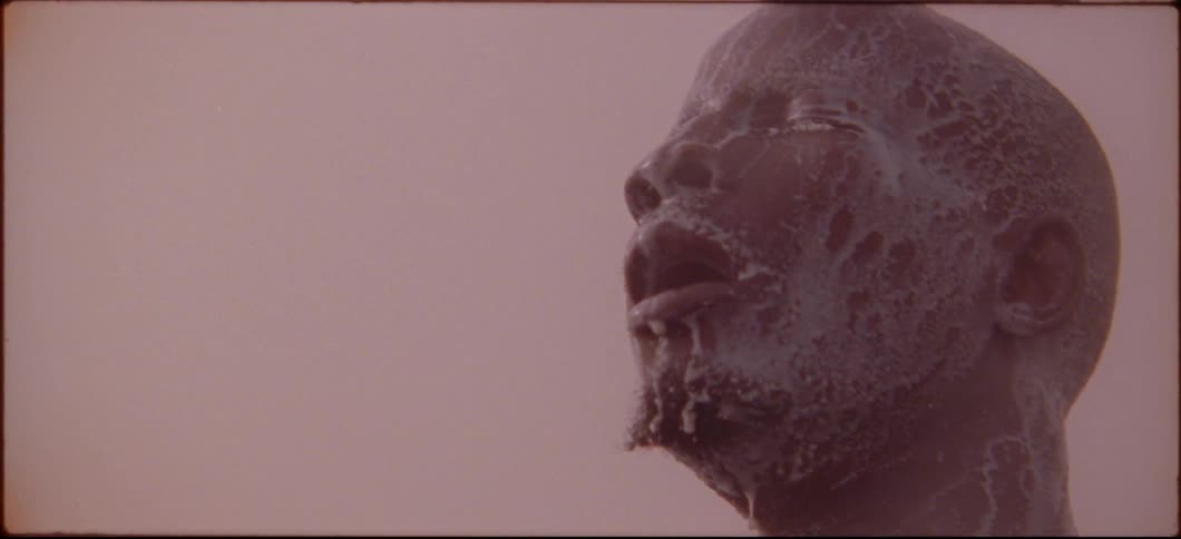 A man with white liquid on his face looks up towards the sky