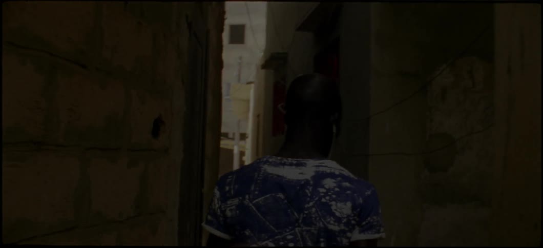A man wearing earbuds walks down a narrow alley