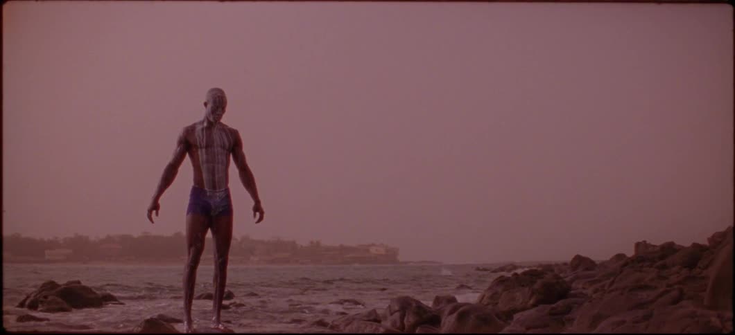 A man standing on a rock in the ocean pours milk on his head
