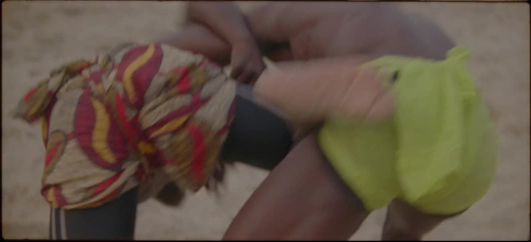People watch as two men wrestle on the beach
