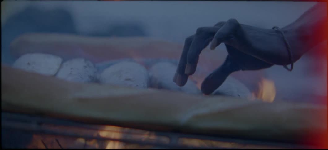 Fish are cooked over a fire on a beach