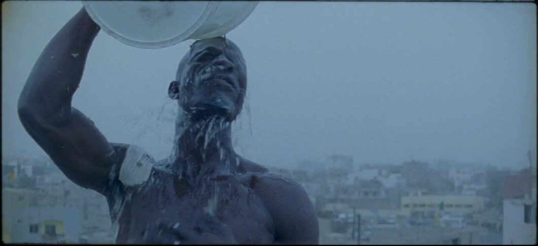 A man pours water from a bucket on his head and chest
