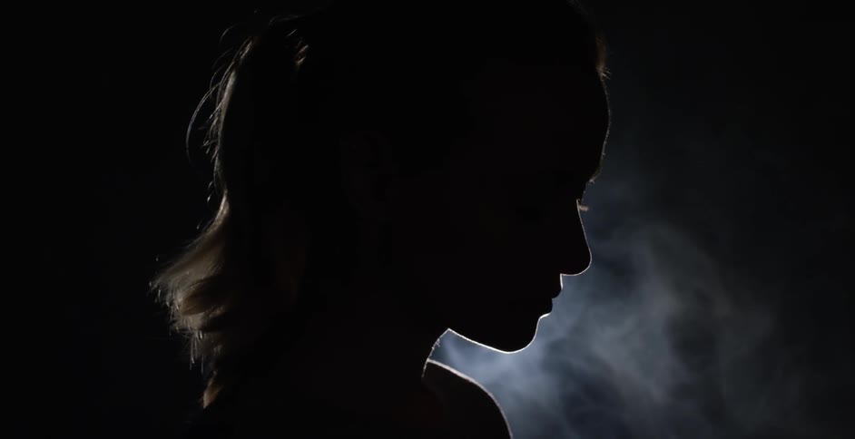 Woman stands contemplating in a dark room