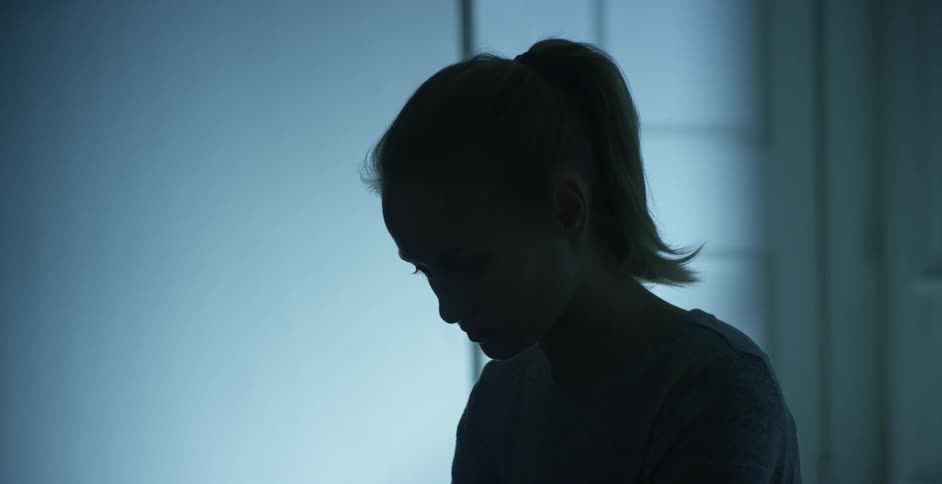 A woman standing and looking forlornly downwards