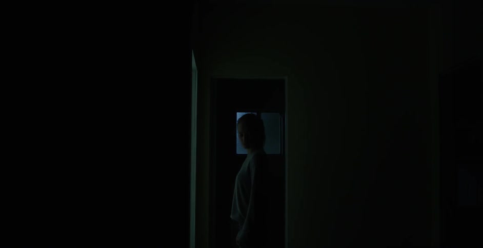 Woman standing in a doorway of a dark room