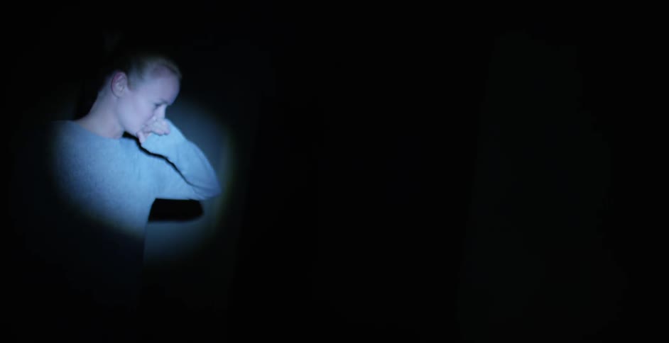 Small spotlight on a woman crying as she moves in a dark area