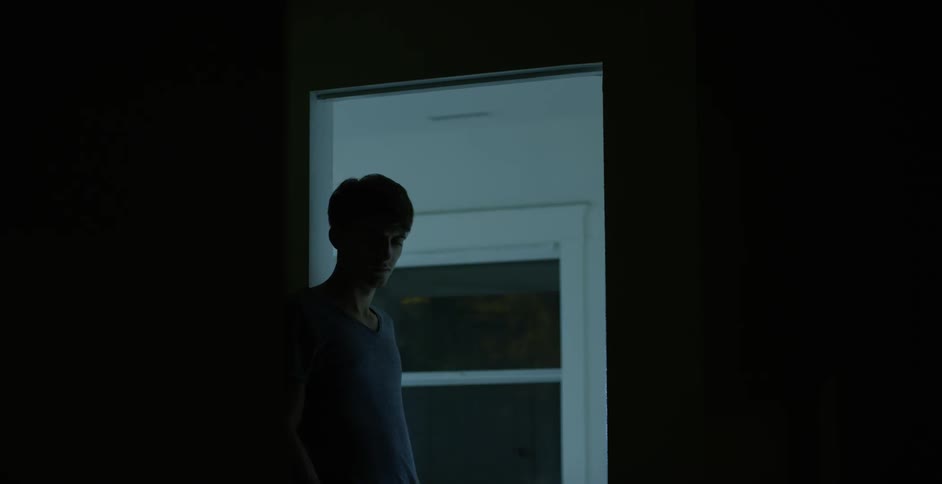 Man is standing in a doorway of a dark room looking around