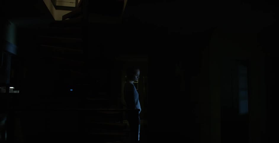 Person wearing blue standing in the dark
