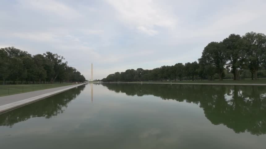 View of a monument across from a large body of water surrounded by a walkway