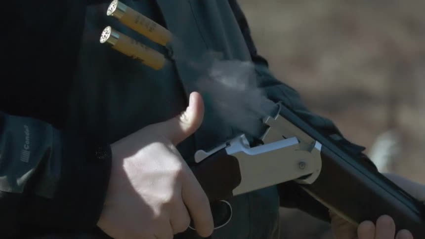 A man holding a rifle while empty casing fly out of the chamber