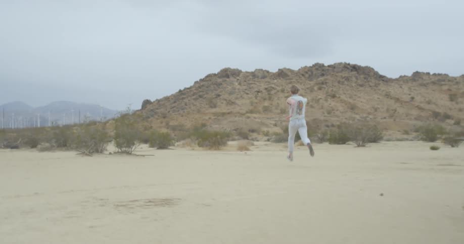 A man in white runs through the desert