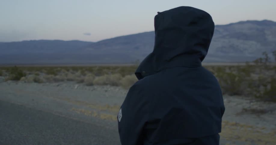 A person in a jacket stands on a road