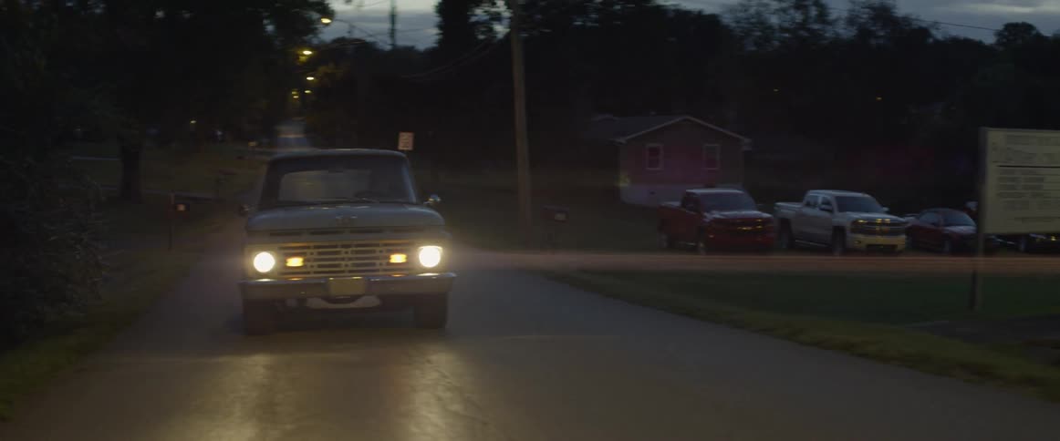 Car drives down a country road at sunset