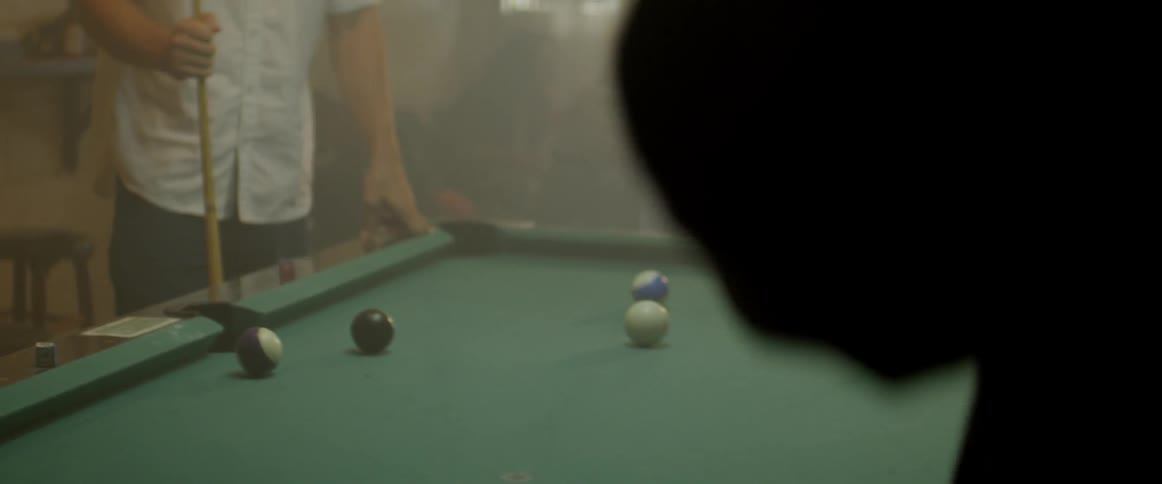 A woman and man play pool in a bar