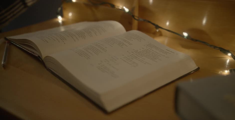 A book lies open on a table next to glowing strand lights