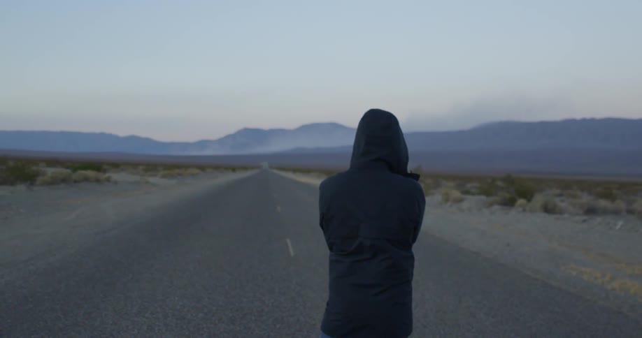 A person in a jacket stands in the road