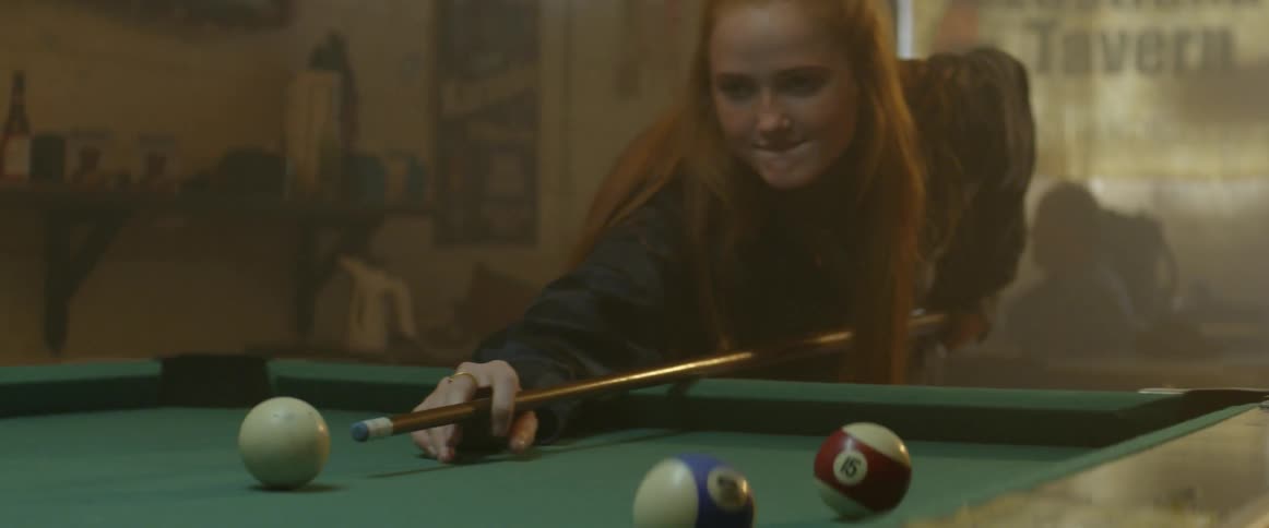 A man and a woman are playing pool in a bar