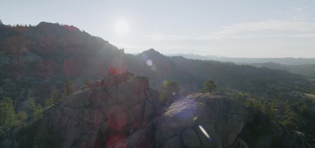 The sun shines over a rocky mountain