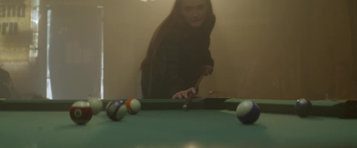 A woman makes a shot in pool