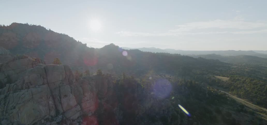 The sun shines over a rocky mountain