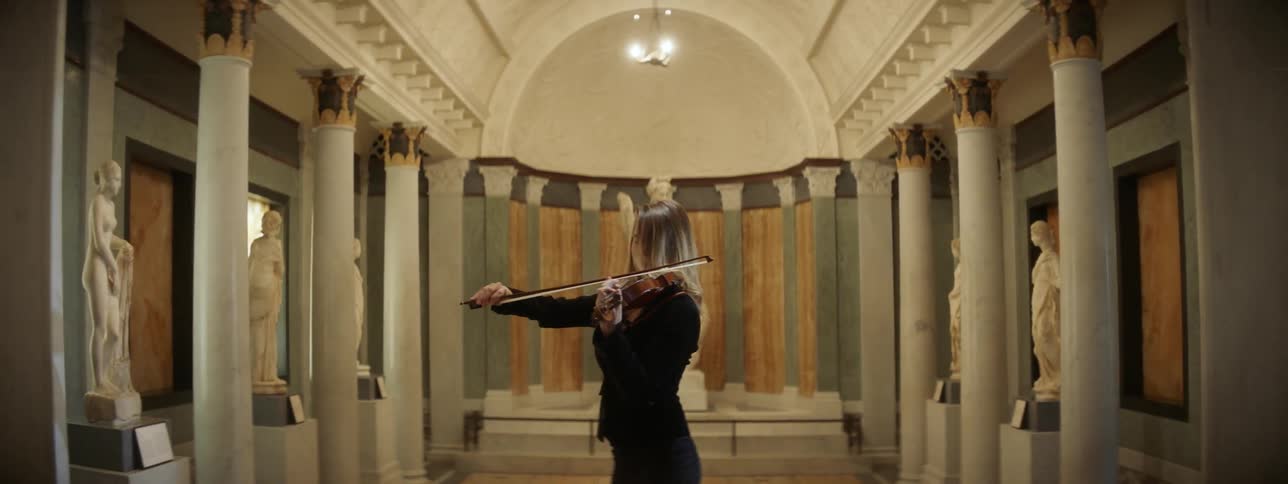 A woman plays violin in a museum