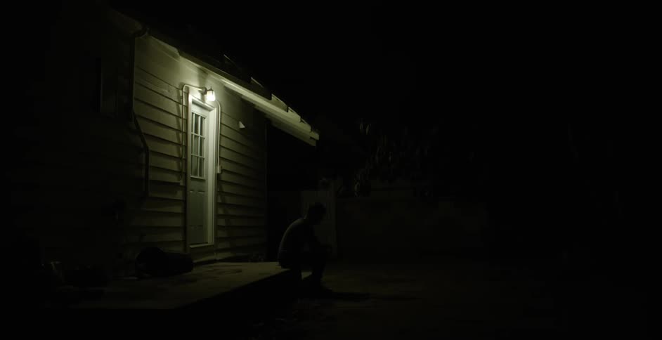 View of a white door with a single light above it at night
