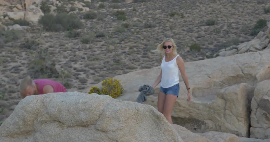 A man and woman walk on rocks