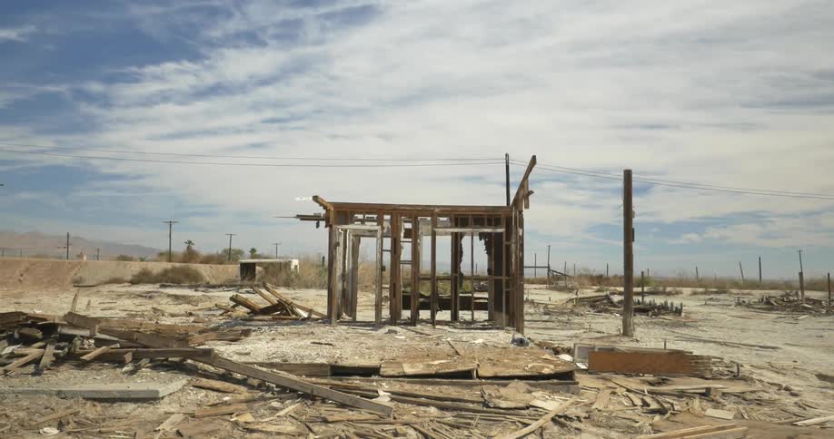Part of a frame of an old building standing in a sandy lot