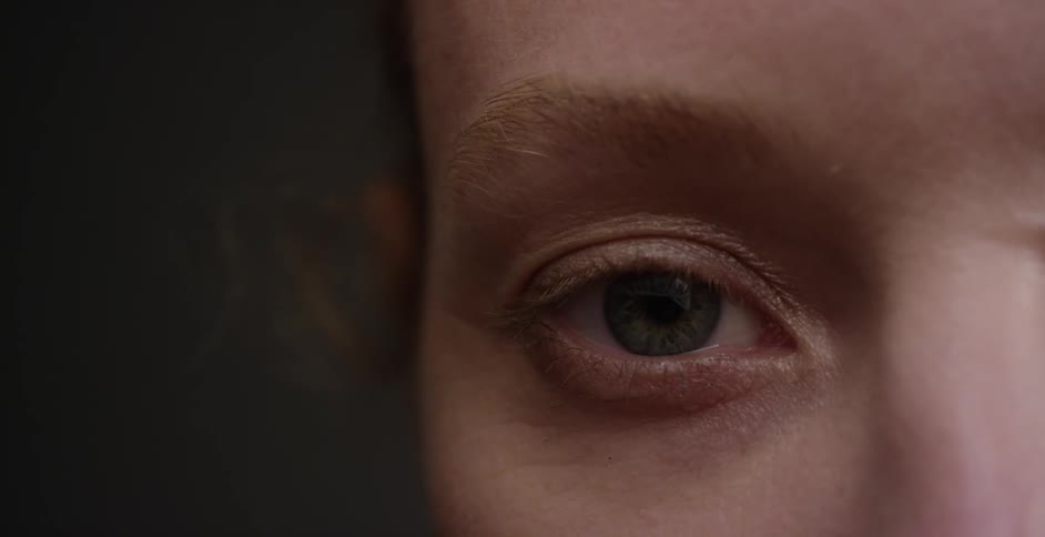 Close up view of a woman opening her blue eyes